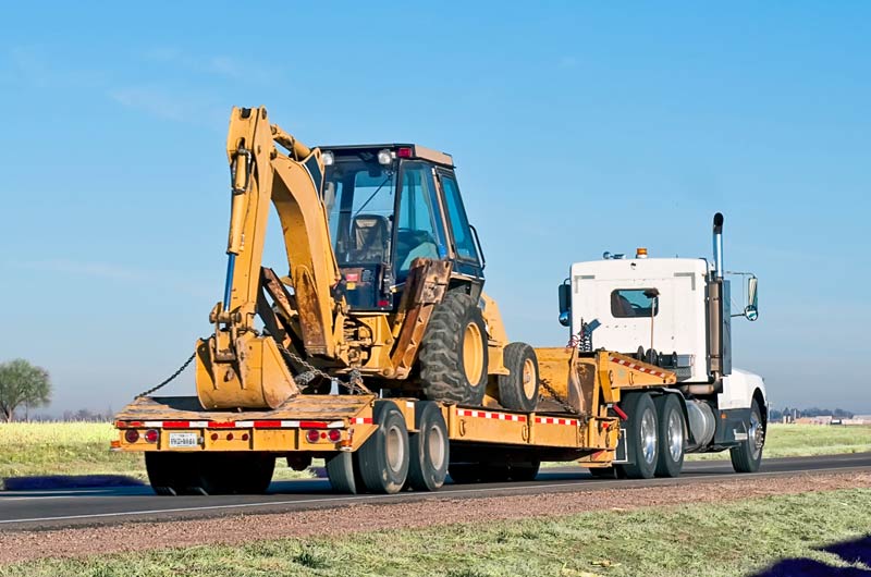 Backhoe being transported for site support services